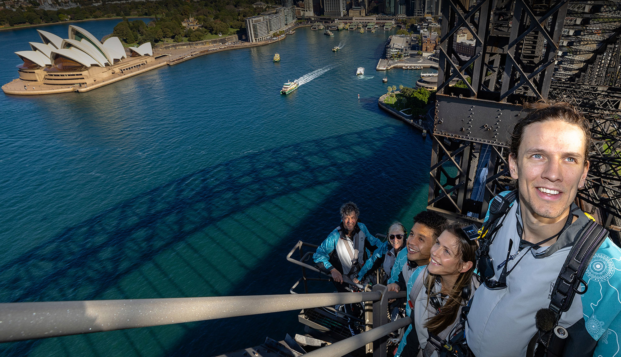 climbers walking along the iconic arches of the sydney harbour bridge with a view of the harbour and the sydney opera house during the vivid sydney festival
