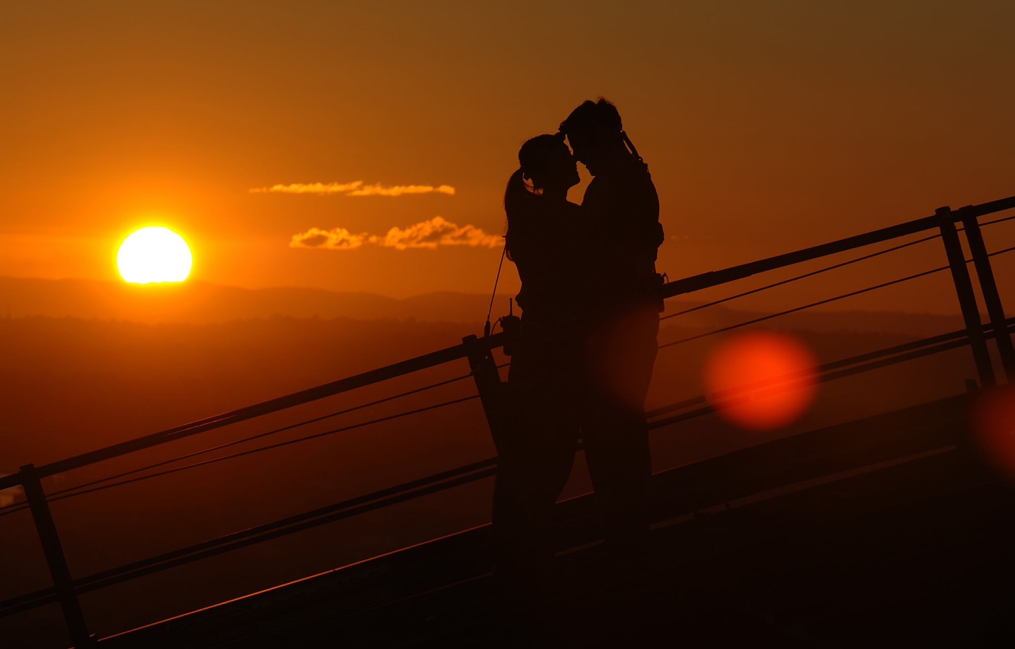 Couple standing on top of the Sydney Harbour Brigde at sunset