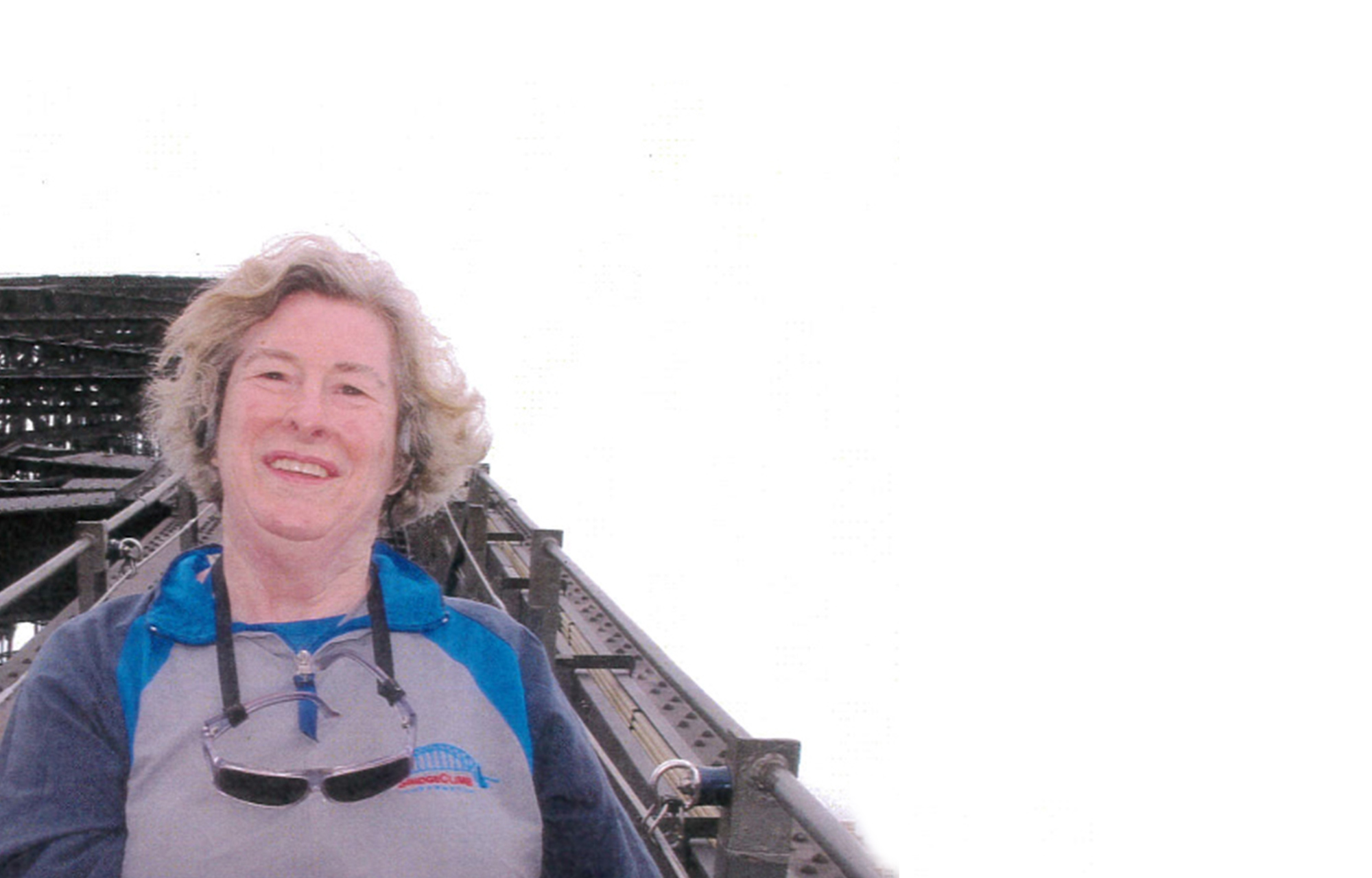 older woman standing on the upper arch of the sydney harbour bridge smiling