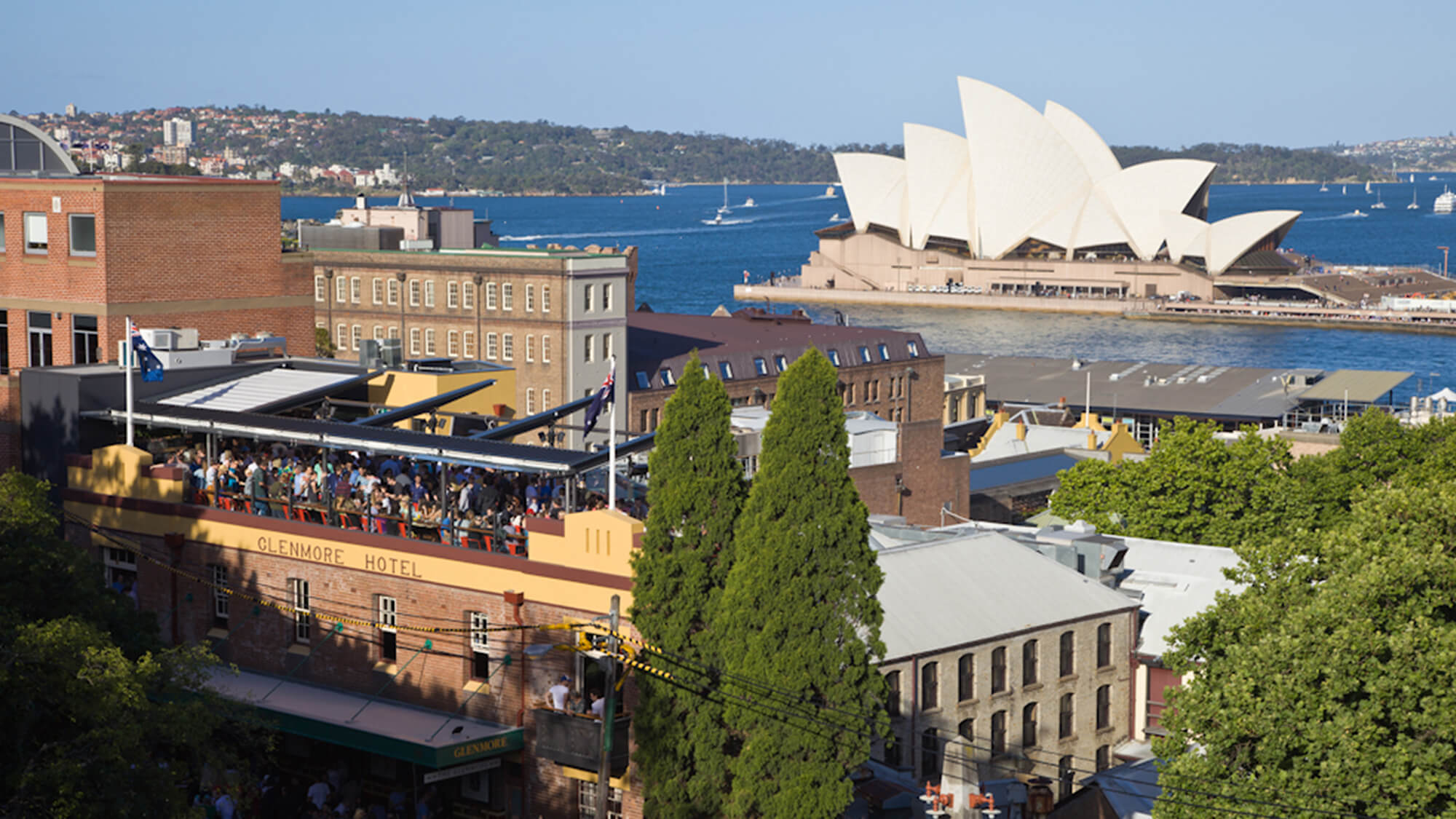 the view of the glenmore hotel rooftop with the opera house and sydney harbour in the background