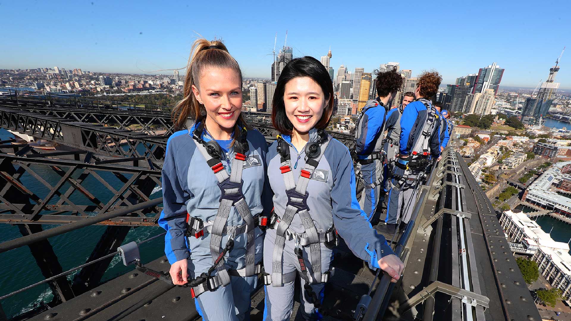two females smiling at the camera enjoying a climb on the upper arch of the sydney harbour bridge