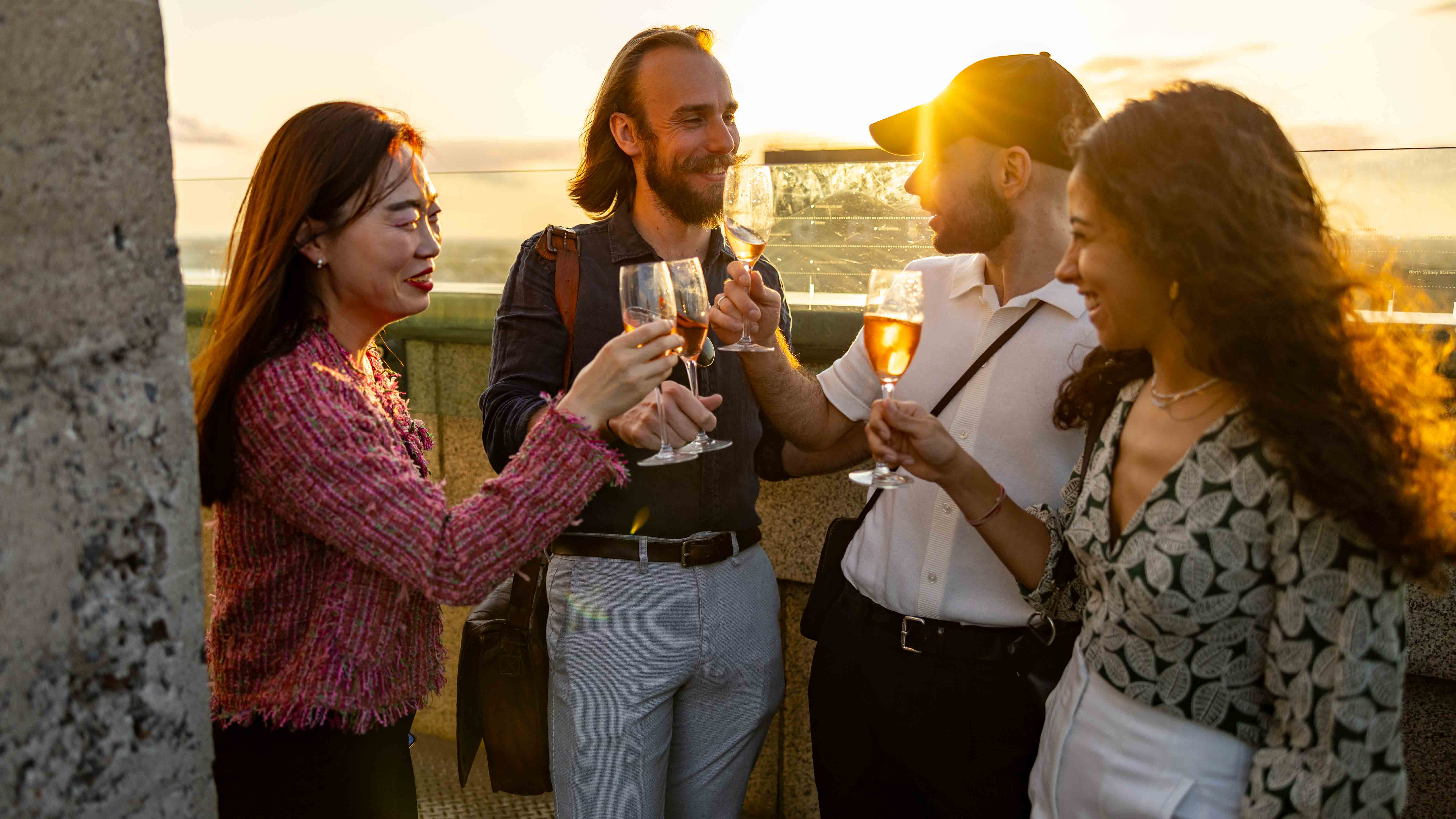group of friends standing at the lookout deck of the pylon with a drink in hand cheersing and smiling